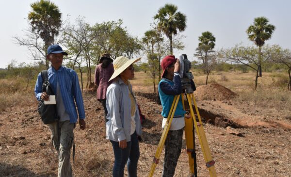 Archaeology student out in the field learning how to use a Total Station