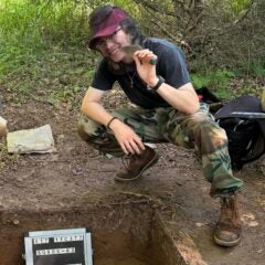 David crouching over an excavated plot holding a trowel