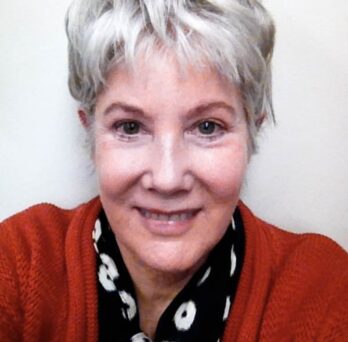 Dr. Roosevelt (woman with white hair, smiling, wearing a coral cardigan) in front of a white background
                  