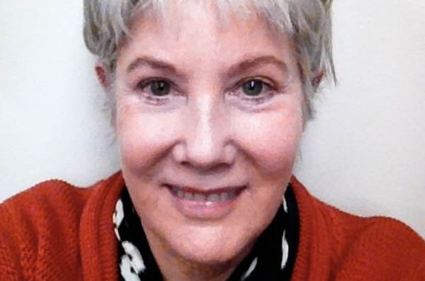 Dr. Roosevelt (woman with white hair, smiling, wearing a coral cardigan) in front of a white background