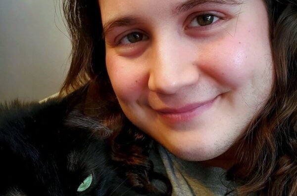 Lukas (man with long brown hair) and a black cat
